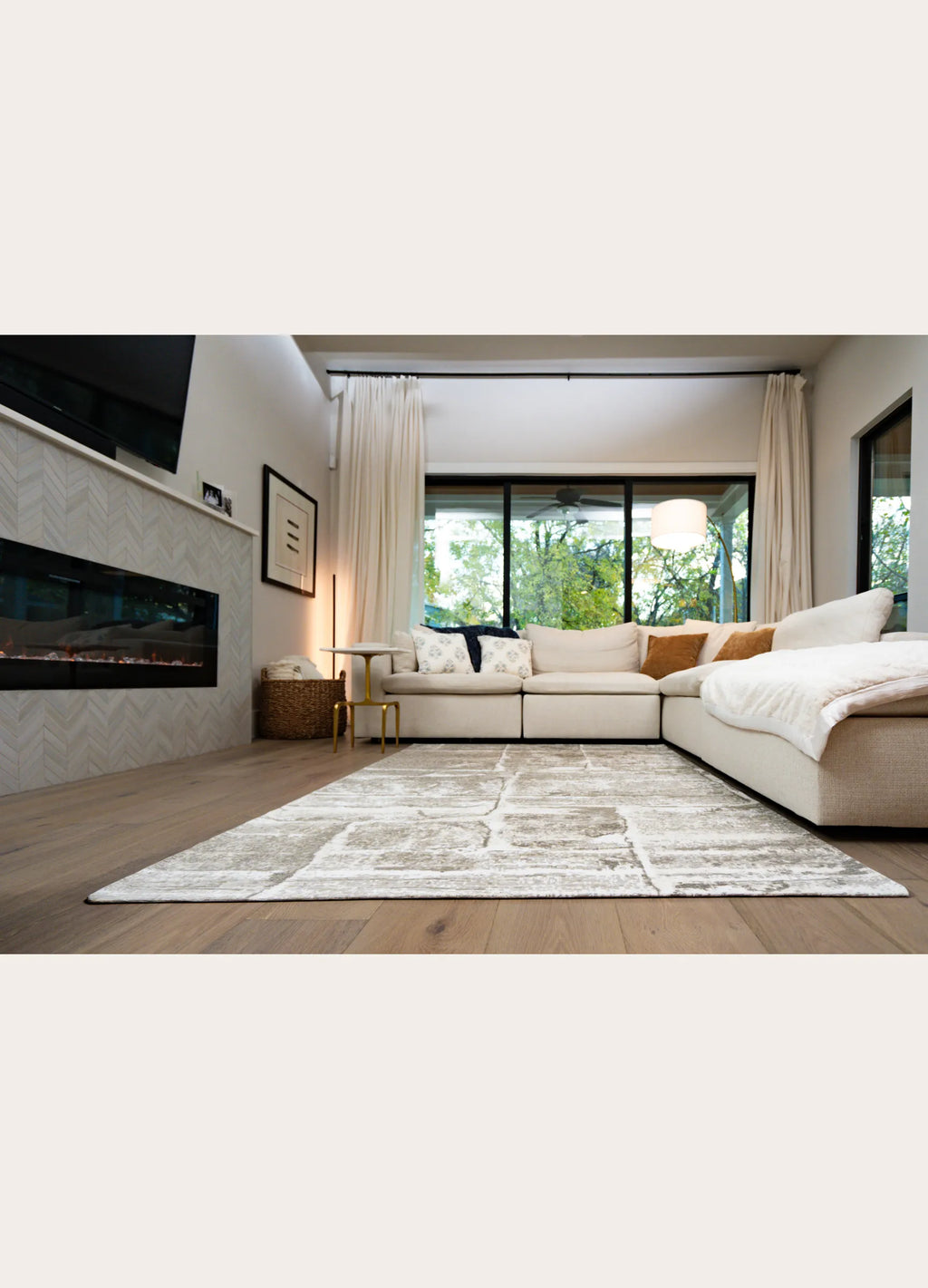 Modern living room with a sectional sofa, rug, and large windows.