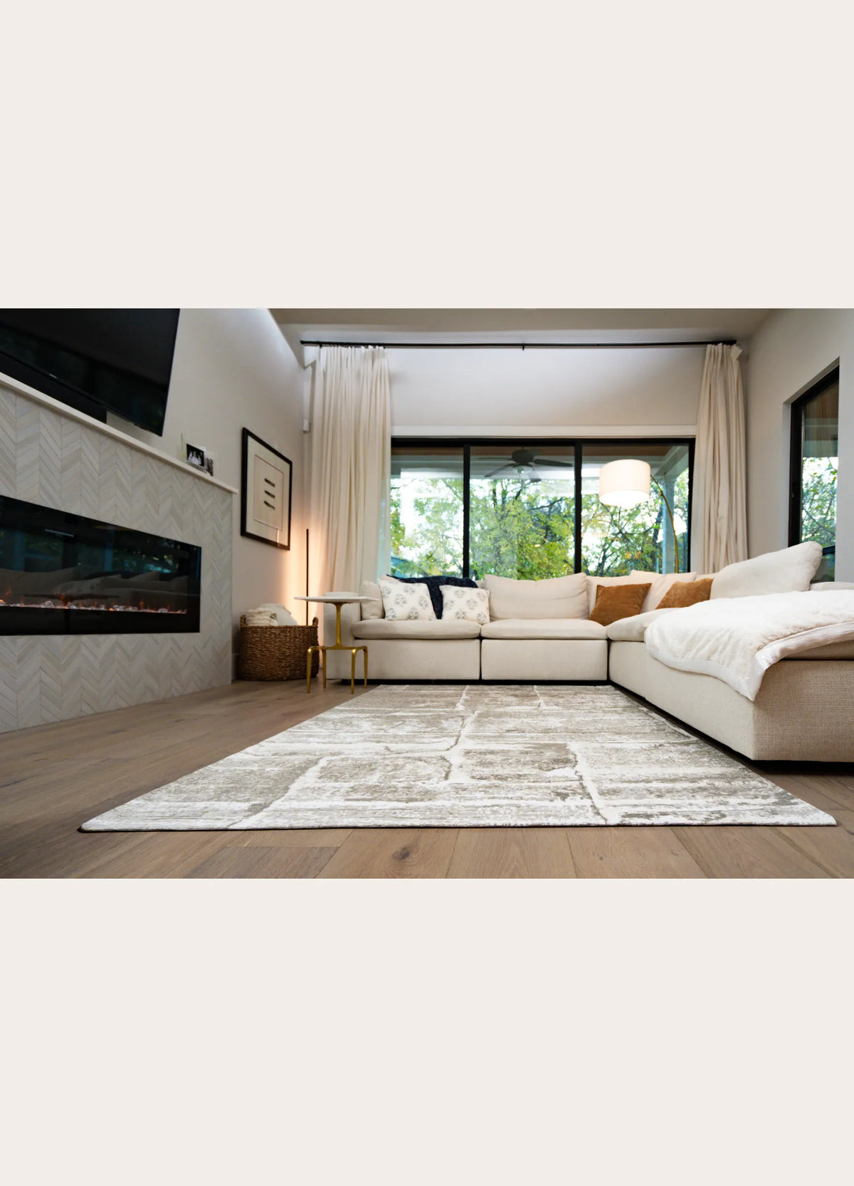 Modern living room with a sectional sofa, rug, and large windows.