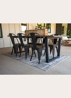 Dining table with black chairs on a rug in a modern living room.