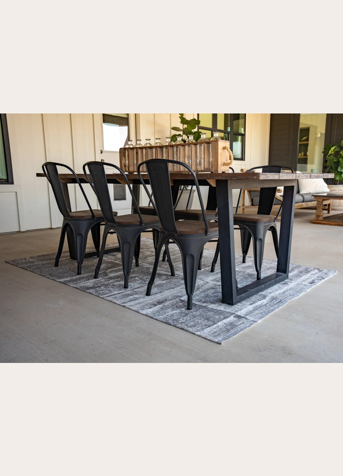 Dining table with black chairs on a rug in a modern living room.